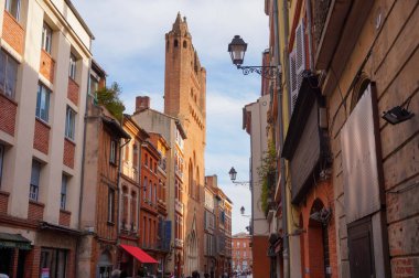Perspective of Rue du Taur, a historical street in the centre of Toulouse, in the South of France, lined with old, traditional brick houses and towered by the bell-tower of Notre-Dame du Taur Church