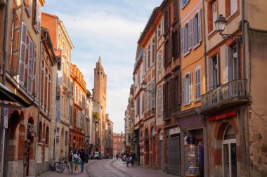 Perspective of Rue du Taur, a historical street in the centre of Toulouse, in the South of France, lined with old, traditional brick houses and towered by the bell-tower of Notre-Dame du Taur Church