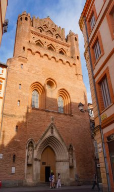 Perspective of Rue du Taur, a historical street in the centre of Toulouse, in the South of France, lined with old, traditional brick houses and towered by the bell-tower of Notre-Dame du Taur Church