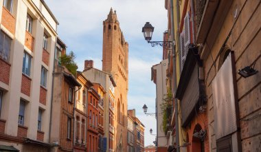 Perspective of Rue du Taur, a historical street in the centre of Toulouse, in the South of France, lined with old, traditional brick houses and towered by the bell-tower of Notre-Dame du Taur Church