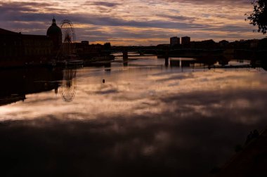 Fransa 'nın Toulouse kentinde Garonne nehrinin üzerinde alacakaranlık etkisi. Kilisenin siluetini çiziyor. Dme de Lagrave, dönme dolap, Pont Saint-Pierre ve Bazacle bölgesi karanlıkta.