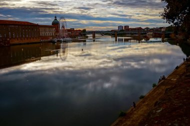 Garonne Nehri 'nin alacakaranlık manzarası Fransa' nın Toulouse şehrinin tarihi merkezine doğru akıyor Saint-Pierre köprüsü ve La Grave Kubbesi 'nin kubbeli kilisesi sudaki yansımalarıyla birlikte.