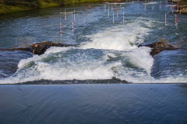 Water falls, rapids and powerful whirlpools with white foam on the River Garonne in Toulouse, France, seen from the passerelle of Chemin de la Loge between the islands of Grand Ramier and Empalot