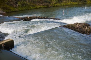 Water falls, rapids and powerful whirlpools with white foam on the River Garonne in Toulouse, France, seen from the passerelle of Chemin de la Loge between the islands of Grand Ramier and Empalot
