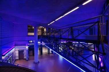 Toulouse, Fransa - Ağustos 2022 - Matabiau Tren İstasyonu metro istasyonunun modern iç mekanı, gece mavi ve mor ışıklarla aydınlatılmış, koridoru kaplayan bir iskelenin metal çerçevesi