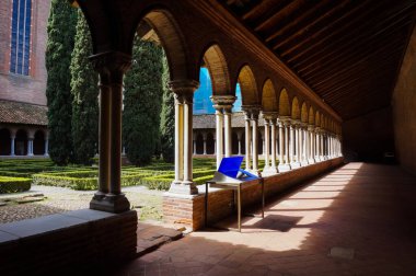 Toulouse, France - April 2019 - Cloister and French garden with cypress tree and trimmed bushes, in the Dominican Convent ofJacobins, a medieval brick monastery housing Thomas Aquinas' burial clipart