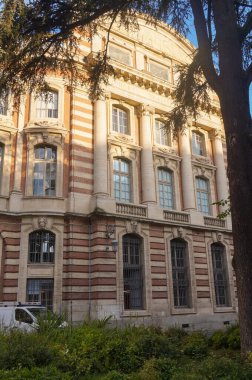 Capitole 'un gerisinde, Fransa' nın Toulouse belediyesinde, heybetli bir tuğla klasik cephesi, büyük sütunları, balkonu olan bir balkon ve üzerinde 