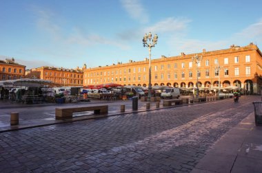 Toulouse, Fransa - Ocak 2020 - Capitole 'un tarihi yaya mahallesinde ikonik dairesel bir meydan olan Place Wilson' da pembe ve turuncu tuğlalarla inşa edilmiş eğri, eski tipik güneyli evler