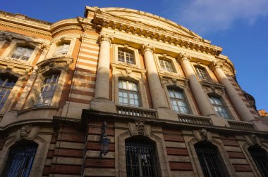 Capitole 'un gerisinde, Fransa' nın Toulouse belediyesinde, heybetli bir tuğla klasik cephesi, büyük sütunları, balkonu olan bir balkon ve üzerinde 