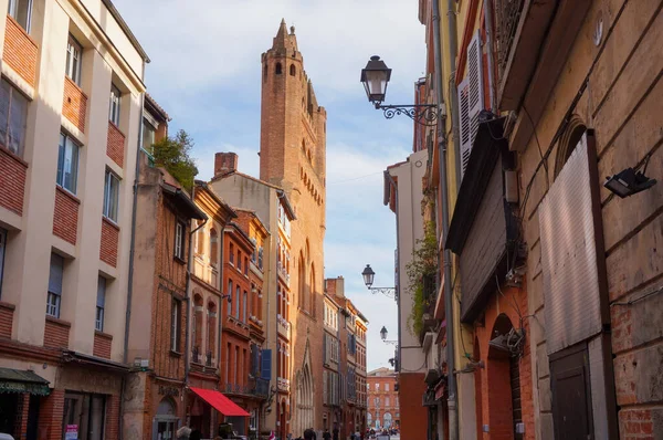 Perspective of Rue du Taur, a historical street in the centre of Toulouse, in the South of France, lined with old, traditional brick houses and towered by the bell-tower of Notre-Dame du Taur Church