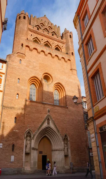 Perspective of Rue du Taur, a historical street in the centre of Toulouse, in the South of France, lined with old, traditional brick houses and towered by the bell-tower of Notre-Dame du Taur Church