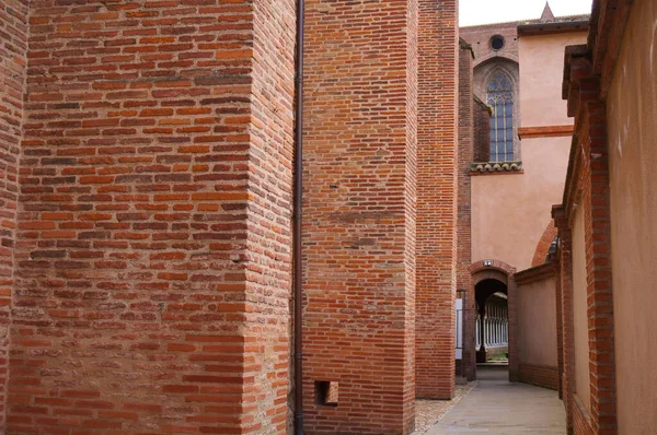 レンガの柱と壁のある典型的な狭い通りは 中世のヤコブ修道院のコロネードにつながり そのステンドグラスの窓は ローズシティ フランスのトゥールーズで — ストック写真