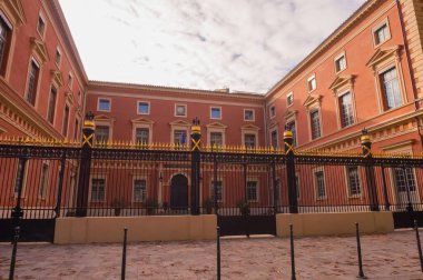 Toulouse, Fransa - Eylül 2019 - Adalet Sarayı 'nın bir parçası olan Temyiz Mahkemesi' nin ön cephesi ve demirden kapısı, kırmızı tuğladan yapılmıştır; kapılar altın mızraklarla süslenmiştir.