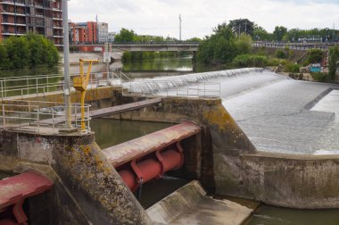 Fransa 'nın Toulouse kentindeki hidrolik silindirlerle hareket ettirilmiş, Tounis mahallesindeki bir kapağın büyük metal kapakçığı, arkada Saint-Michel köprüsünün altından Garonne nehri akıyor.