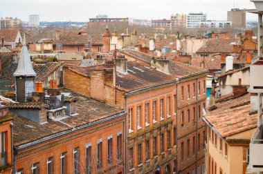 Toulouse, France - Jan. 2021 - Elevated view in long focal length on the old, typical brick town buildings of Rue des Prtres Street, in Les Carmes, a historic neighborhood in the center of the city
