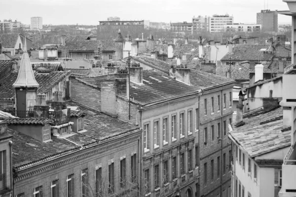 Toulouse, France - Jan. 2021 - Old brick townhouses, with typical louvered shutters and shops on the ground floor, by Rue des Filatiers Street, in the historic neighborhood of Carmes (black and white)