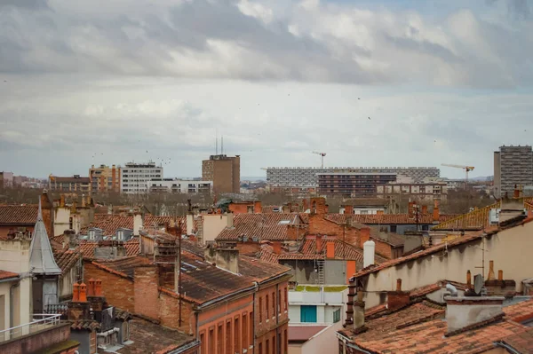Toulouse, France - Feb. 2020 - Typical brick southern townhouses seen from the multi-storey car park in Place des Carmes, in the most expensive neighborhood of Toulouse, featuring old wooden shutters