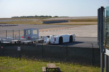 Vatry, Fransa - 9 Eylül 2023 - Chlon-en-Champagne yolu üzerinde yer alan Paris-Vatry Havaalanı 'nda pistin yanında ve çitin arkasında römorklu bir traktör ve bagaj vagonu