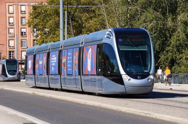 Toulouse, Fransa - 7 Ekim 2023 - Tisso Line T1 'deki tramvay, Saint-Michel Köprüsü' nden geçer; Toulouse tramvayı Fransız üretici Alstom tarafından tasarlanır ve Airbus tarafından tasarlanır.