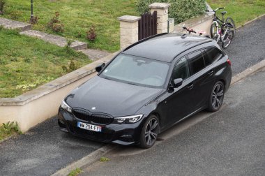 Aveyron, Fransa - 1 Şubat 2023 - Hatchback versiyonunda siyah 2018 BMW 3 Serisi, Alman premium otomotiv üreticisi BMW tarafından üretilen özel bir araba, kaldırım kenarında, bir ağacın gölgesinde park edilmiş.