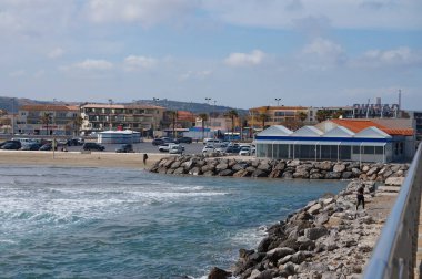 Port-la-Nouvelle, Fransa - 5 Nisan 2024 - Akdeniz kıyısında bir sahil beldesi olan Port-la-Nouvelle 'deki deniz fenerinden, taştan iskelelerden ve Güney Avrupa tarzı evlerden görüntüler