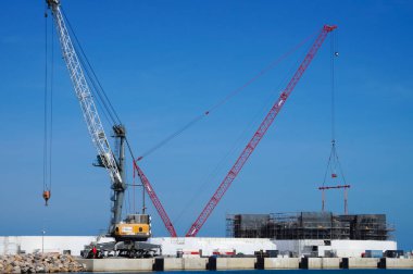 Port-la-Nouvelle, France - April 6, 2024 - A mobile harbor crane and a luffing-jib crane on the construction site for the extension of Port-la-Nouvelle commercial harbor, on the Mediterranean Sea clipart