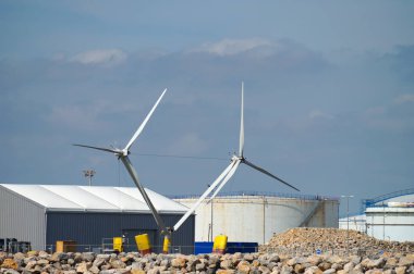 Port-la-Nouvelle, Fransa - 5 Nisan 2024 - Port-la-Nouvelle ticari limanında açık deniz rüzgar türbinleri montaj altında; arka planda, bir petrol deposunda dairesel tanklar