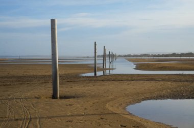 Port-la-Nouvelle, Fransa - 5 Nisan 2024 - Akdeniz kıyısındaki Montilles kumsalında, Narbonne bölgesinde, kıyı şeridini dengelemek için metal yığınları şeklinde bir dalgakıran vardır.