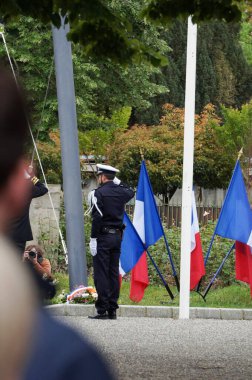 Toulouse, France - May 8, 2024 - A police officer salutes while a wreath of flowers is being laid at the War Memorial, which has been adorned with French flags for the commemoration of the Victory Day clipart