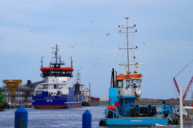 Port-la-Nouvelle, Fransa - 5 Nisan 2024 - Akdeniz kıyısındaki ticari limanın mısır gevreği terminalinde çok amaçlı bir tekne, bir elektrikli hopper dredger ve genel bir kargo