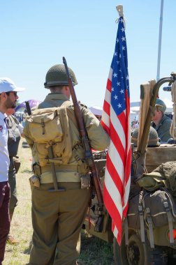 Lherm, Fransa - 11 Mayıs 2024 - Hava Fuarı sırasında Muret-Lherm havaalanında Amerikan askeri kampının tarihi yeniden canlandırması: Amerikan bayrağının yanında duran bir adam