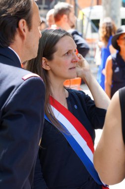 Toulouse, France - July 14, 2024 - Member of the National Assembly Anne Stambach-Terrenoir (NFP, far-left), wearing the official parliamentary tricolor sash, attends the National Day military parade clipart