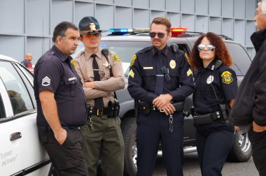 Aussonne, Fransa - 7 Eylül 2024 - Los Angeles, CA ya da Panama City, FLA 'den gelen ABD' li polis memurları gibi giyinen Extras, MEETT 'deki Auto Moto Classic autoshow' da Amerikan polis arabalarının yanında beklemektedir.