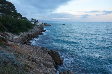 Antibes, Fransa - 25 Ekim 2024 - Cte d 'Azur' da (Fransız Rivierası) lüks bir sahil beldesi olan Cap d 'Antibes yarımadasının kayalık kıyılarında, yabani bir koydan Akdeniz' e gece görüşü)