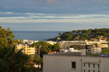 Antibes, Fransa - 21 Ekim 2024 - Akdeniz kıyısındaki Juan-Les-Pins sahil beldesi Cte-d 'Azur' dan (Fransız Rivierası), Cap d 'Antibes yarımadasının Garoupe tarafında gün batımı manzarası