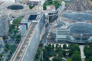 Paris, France - June 22, 2024 - Top view from Tour Montparnasse over the modern Maine-Montparnasse District: Atlantique Gardens, curved glass office buildings, train station, enclosed circulars quares clipart