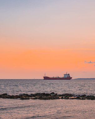 Alacakaranlıkta limanın yanında bir kargo gemisi duruyor.