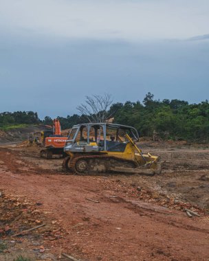 Balikpapan, Endonezya - 10 Mart 2024 Bu buldozerler kirli bir araziye parkedilmiş, kılıçları çalışmaya hazır. Arazi temizliği ve toprak taşıma projeleri için inşaat ekipmanları.