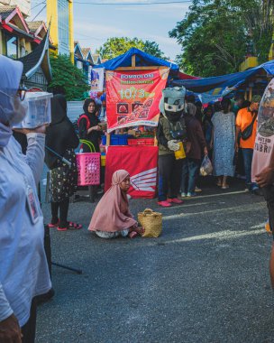 Balikpapan, Endonezya - 22 Mart 2024 İnsanların ona biraz para vermesini bekliyor.