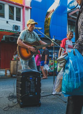 Balikpapan, Endonezya - 22 Mart 2024 Gitarı ve mızıkasıyla popüler şarkıları söylüyor.