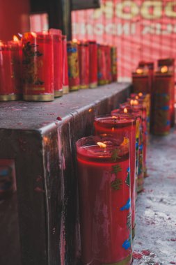 Jakarta, Endonezya - 7 Mayıs 2024. Bir sıra kırmızı mum ve balmumunda ejderha desenleri var. Mumlar sıcak ışıkla yıkanmış metal bir rafta duruyor..