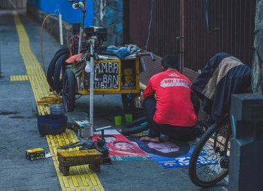 Jakarta, Endonezya - 11 Mayıs 2024 Lastiği onarıyor. Ve arabası ekipmanla dolu..