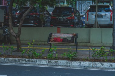 Jakarta, Endonezya - 11 Mayıs 2024 Çocuk ofis otoparkının yakınında uyuyor..