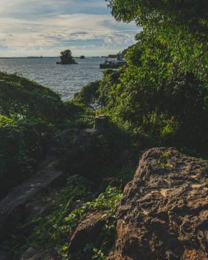 Endonezya, Balikpapan 'da gün batımının sıcacık ışıklarıyla yıkanan kayalık bir sahil manzarası..