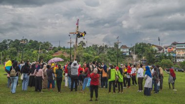 Balikpapan, Endonezya - 18 Ağustos 2024. Dişi dağcı palmiye ağacı tırmanışı veya panjat pinang yarışması sırasında kalabalık tarafından alkışlanır..