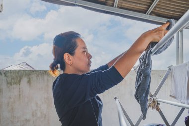 Balikpapan, Endonezya - 4 Ağustos 2024. Elbiseleri alüminyum çamaşır ipine geçirir..