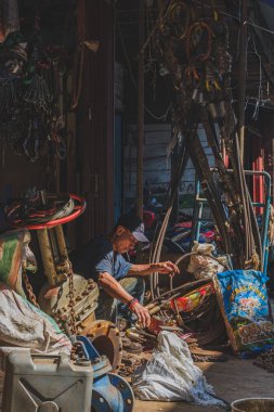 Balikpapan, Endonezya - 26 Haziran 2024 Tüccar güneşli bir günde eski dükkanının önünde bazı eşyalar ayırıyor..