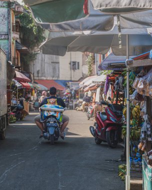 Balikpapan, Endonezya - 26 Haziran 2024. O, Pandan Sari geleneksel pazarından eve dönerken motosikletinin arka koltuğunda bir çuval pirinç taşıyor..