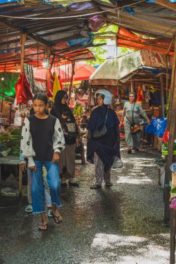 Balikpapan, Endonezya - 26 Haziran 2024. Diğer kızlarıyla birlikte çamurlu Pandan Sari pazarında yürüyorlar..