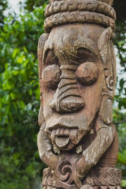 Balikpapan, Endonezya - 29 Eylül 2024. Yıpranmış bir Dayak kabilesinin yakın çekimi ahşap totem direğinin detaylı oyulmuş bir yüzü büyük gözleri ve büyük burnu var..